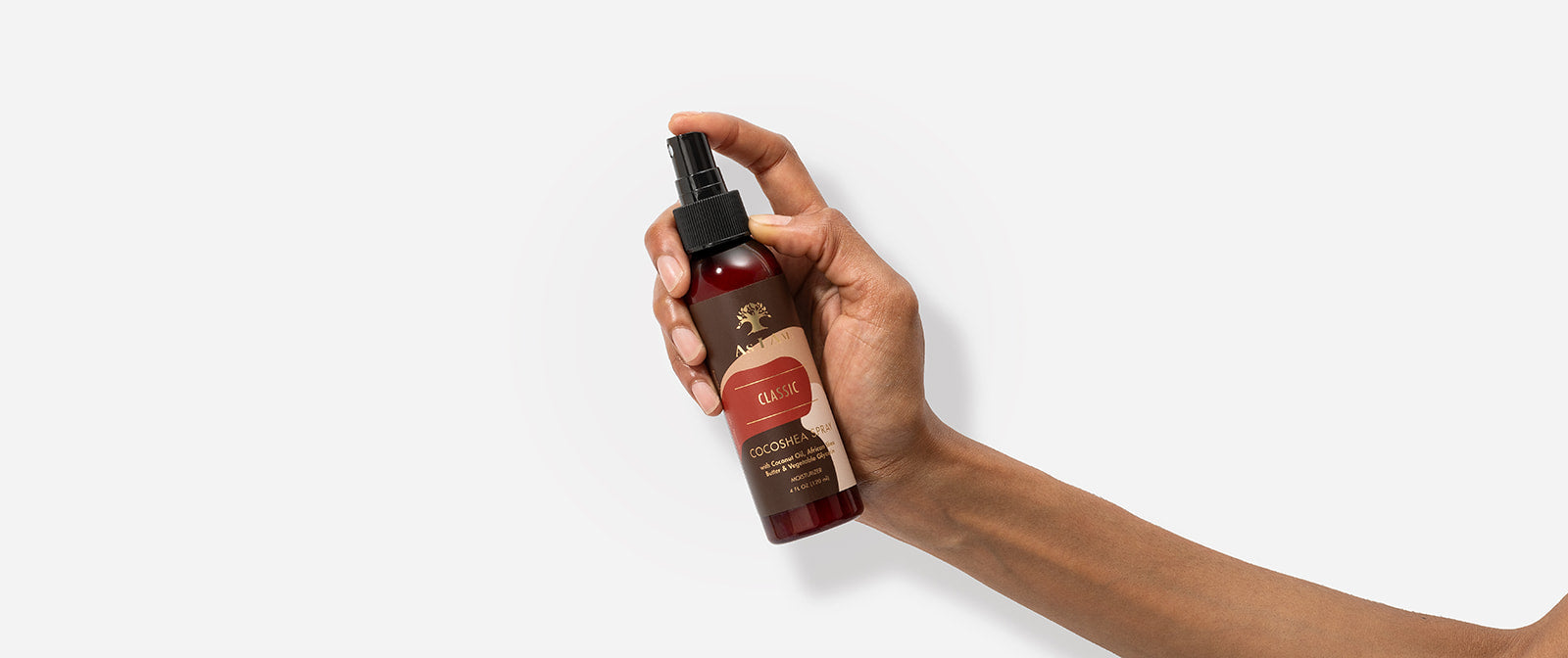 Hand holding a bottle of hair care product with a white background