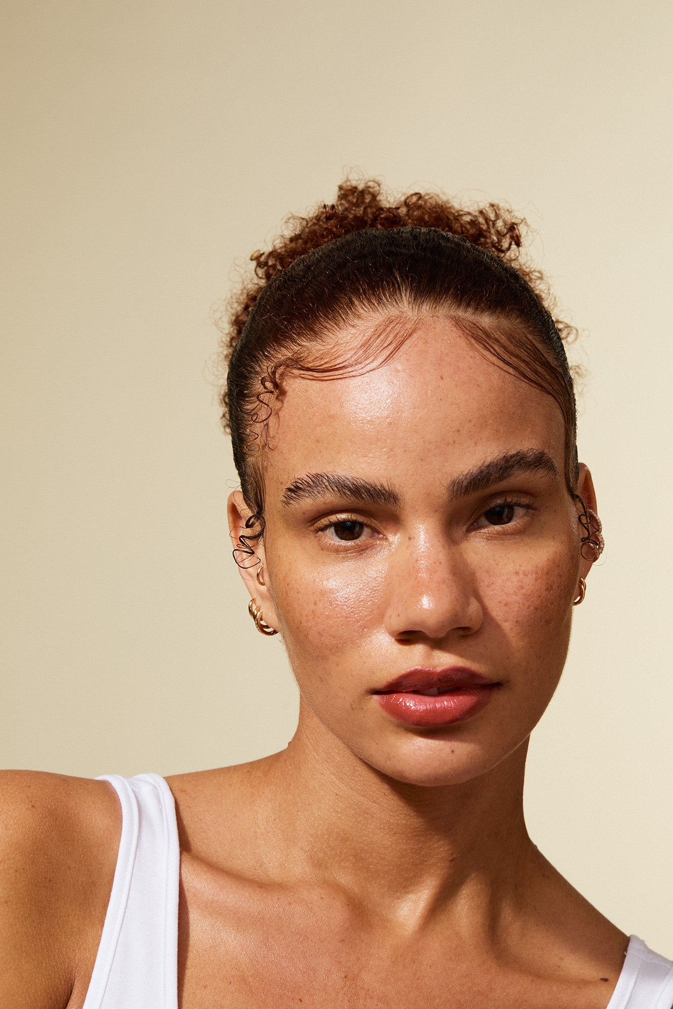 Woman with a bun hairstyle against a beige background