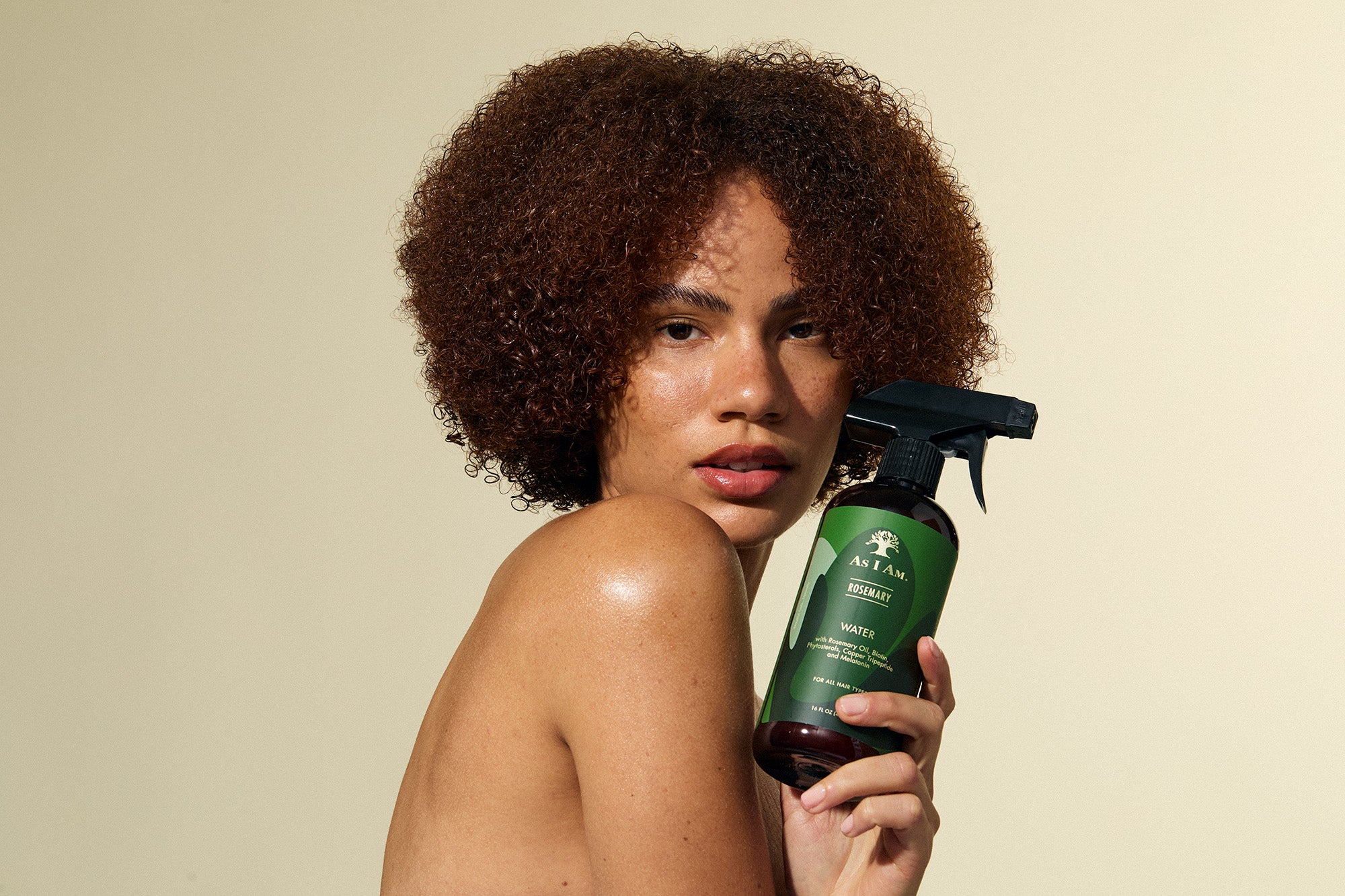 Woman holding a green hair care product with a beige background