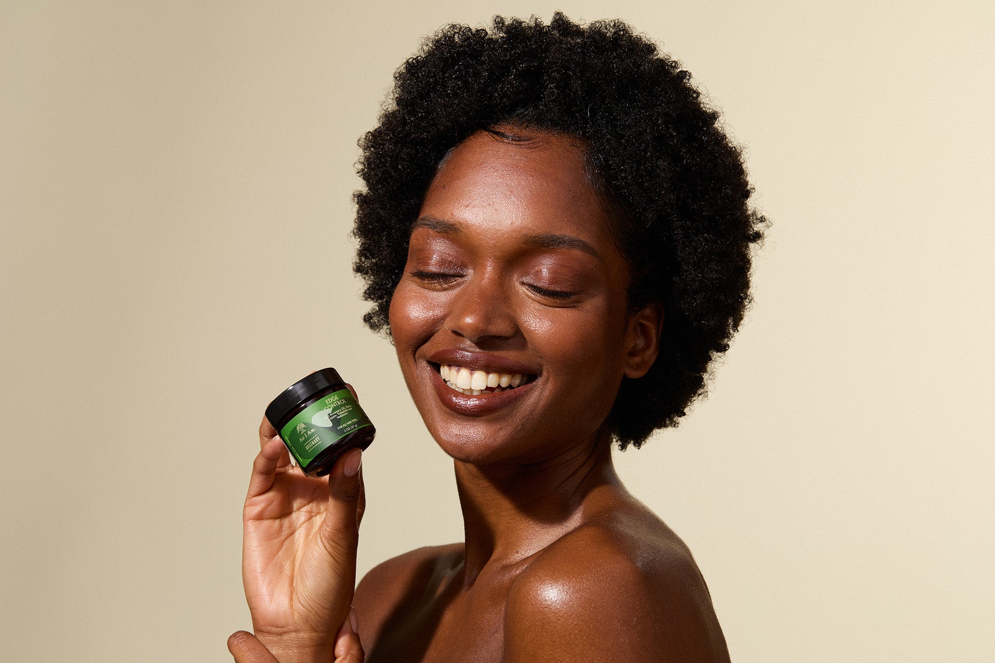 Woman holding a green jar of cream against a beige background