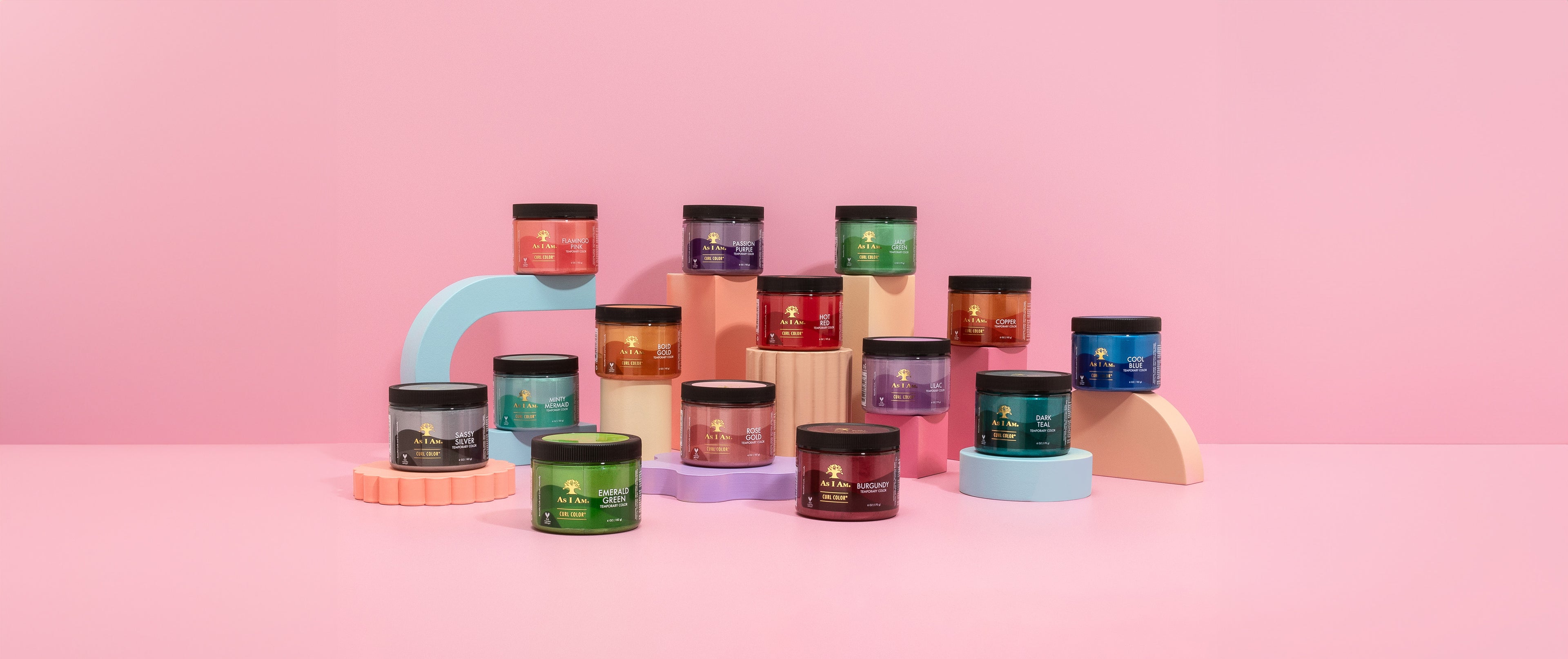 Colorful cosmetic jars on a pink background