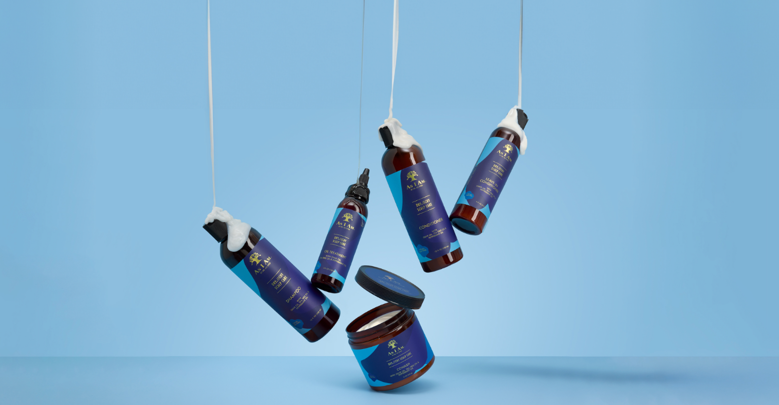 Blue hair care product bottles hanging against a blue background