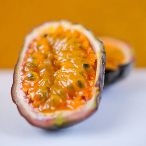 Halved passion fruit on a white surface with an orange background