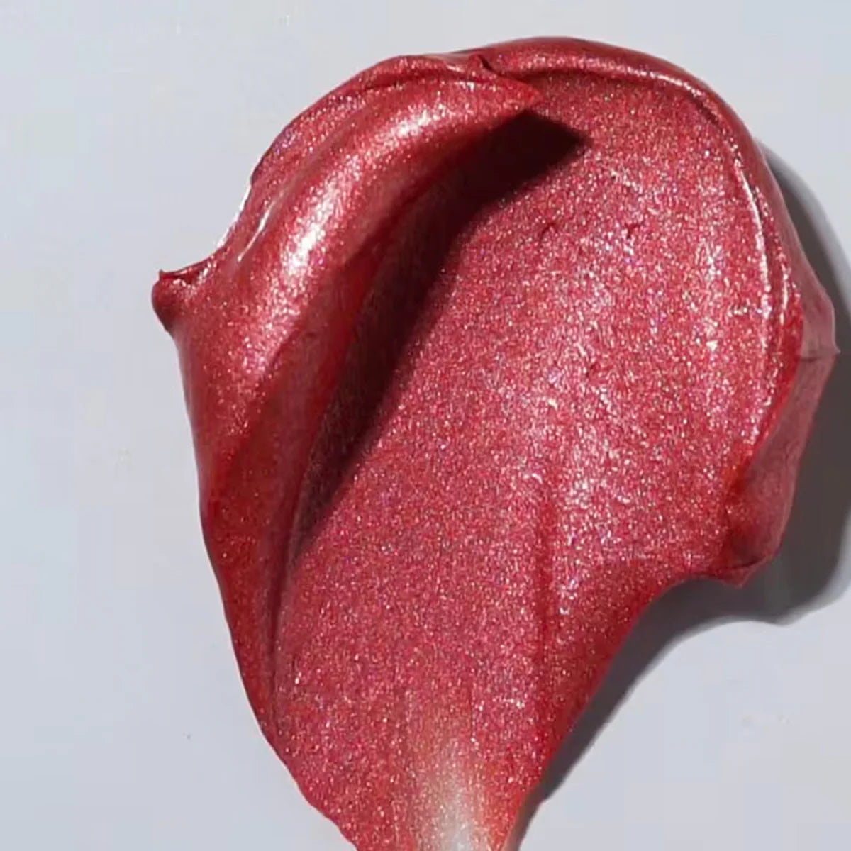 Close-up of a swatch of pink glittery makeup on a white background