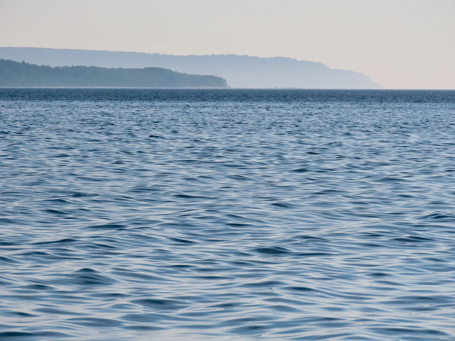 Calm blue water with a distant shoreline under a clear sky